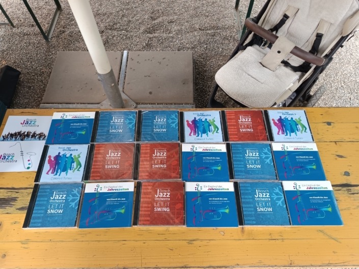 CDs mit Jazzmusik liegen auf einem Holztisch neben einem Kinderwagen.