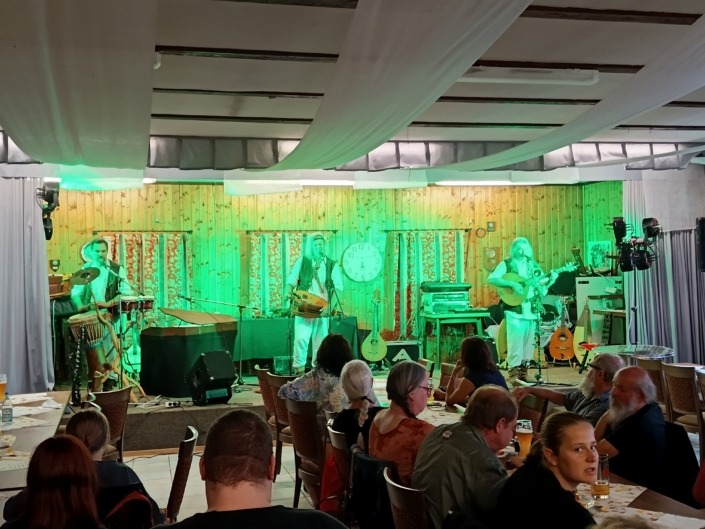 Eine Band spielt auf einer Bühne vor Publikum in einem Raum mit grüner Beleuchtung.